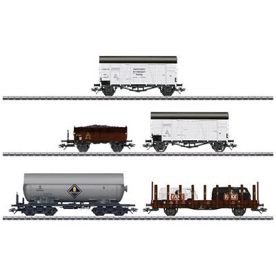 Four model railway wagons: two goods wagons, a tanker wagon and a flatbed wagon with barrels and crates, on parallel tracks.