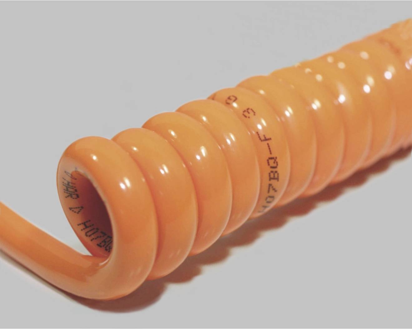 Orange spiral cable on a grey background, partially visible with printed text.