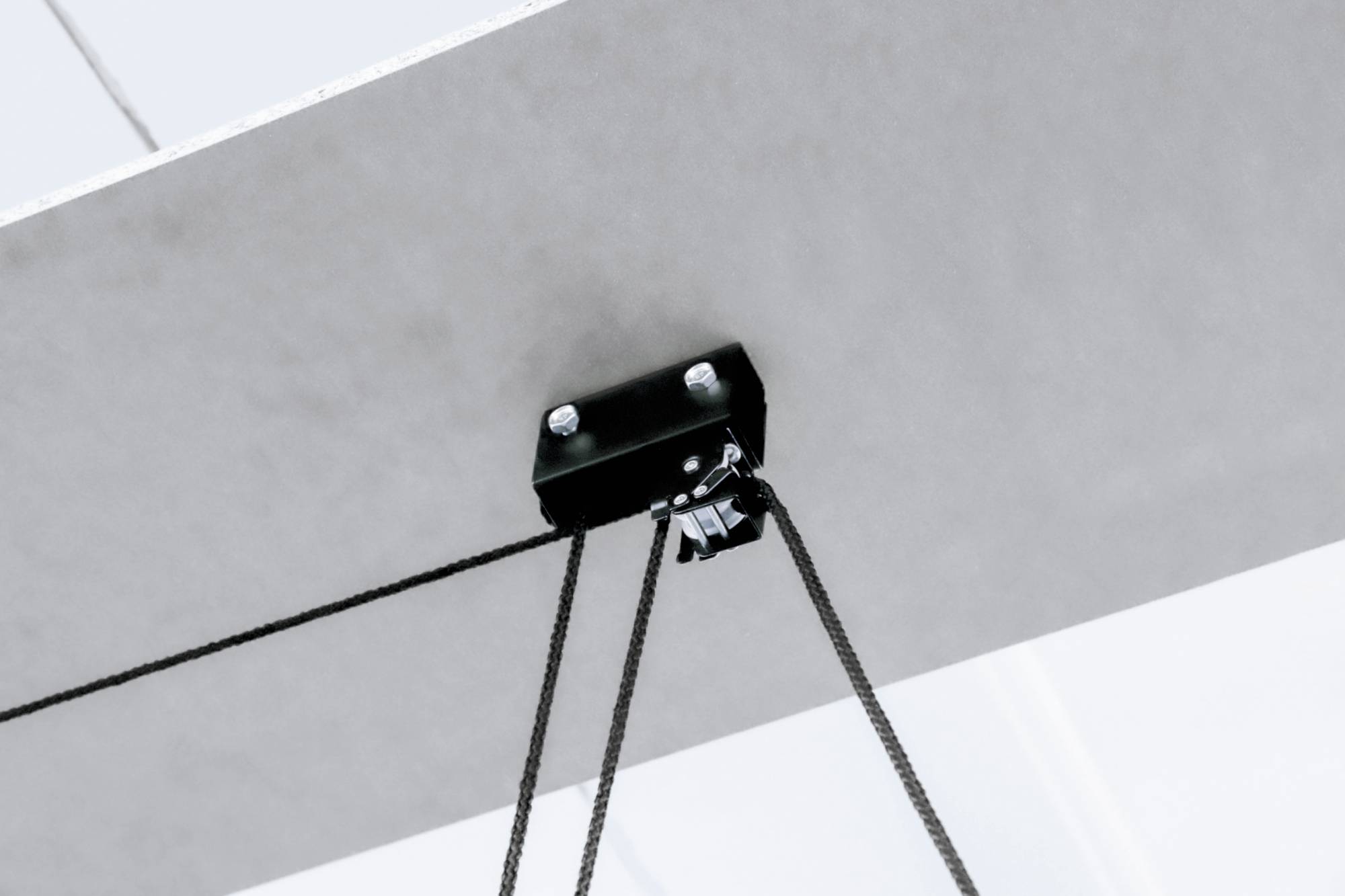 A black rope support mounted on a ceiling, holding multiple ropes.