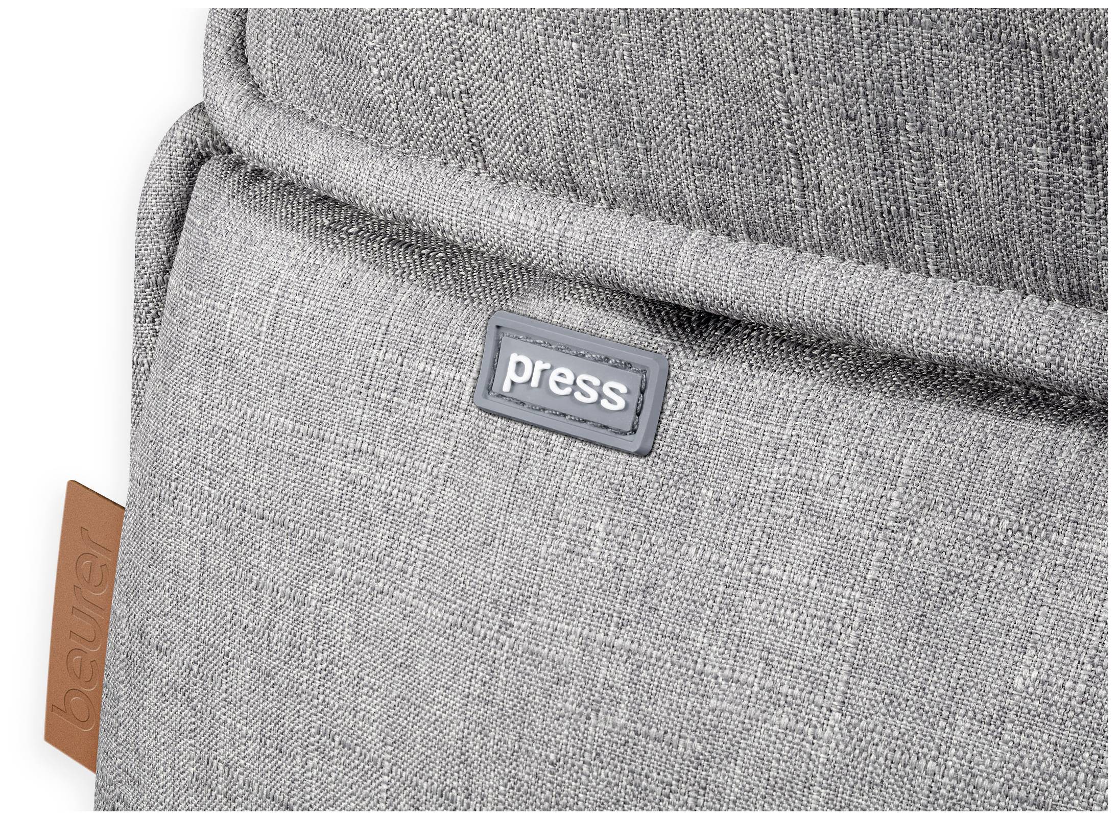 Grey fabric with a small, sewn-on label displaying the word 'press' on a dark background. A brown label is visible in the bottom right corner.