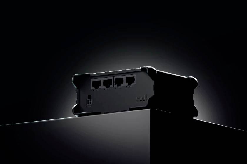 Black technical device with four network ports, illuminated on a podium against a black background.