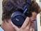 A person is wearing black headphones and listening to music intently. The headphones have a 'Hercules' logo on the ear cup.