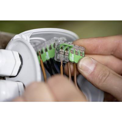 Close-up of two hands inserting wires into an electrical socket, demonstrating the connection process.