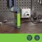The image shows a green torch, plugged into a socket, on a wooden surface in front of a perforated wall with tools.