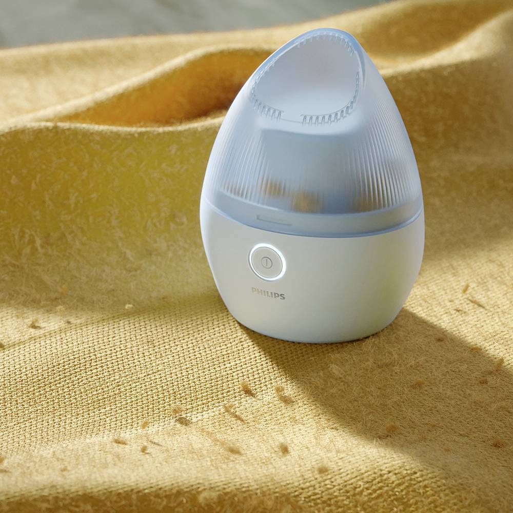 A small, illuminated humidifier sits on a yellow fabric.