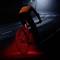 A cyclist with a red rear light is riding at night on an empty street. The headlight illuminates the path ahead of him.