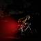 A cyclist is riding on a dark road at night. A red rear light is illuminating on the bicycle, ensuring visibility.