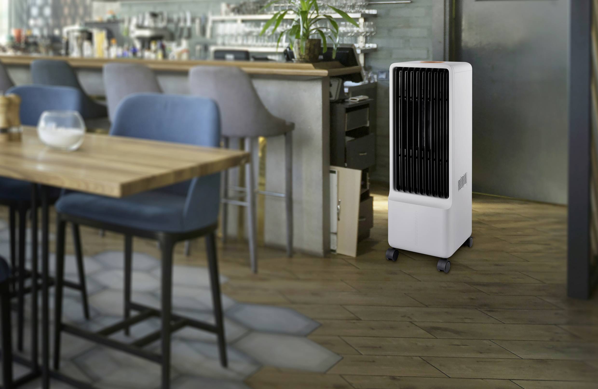 Mobile air cooler in a café, positioned next to bar stools and the bar counter. The space looks modern and cosy.