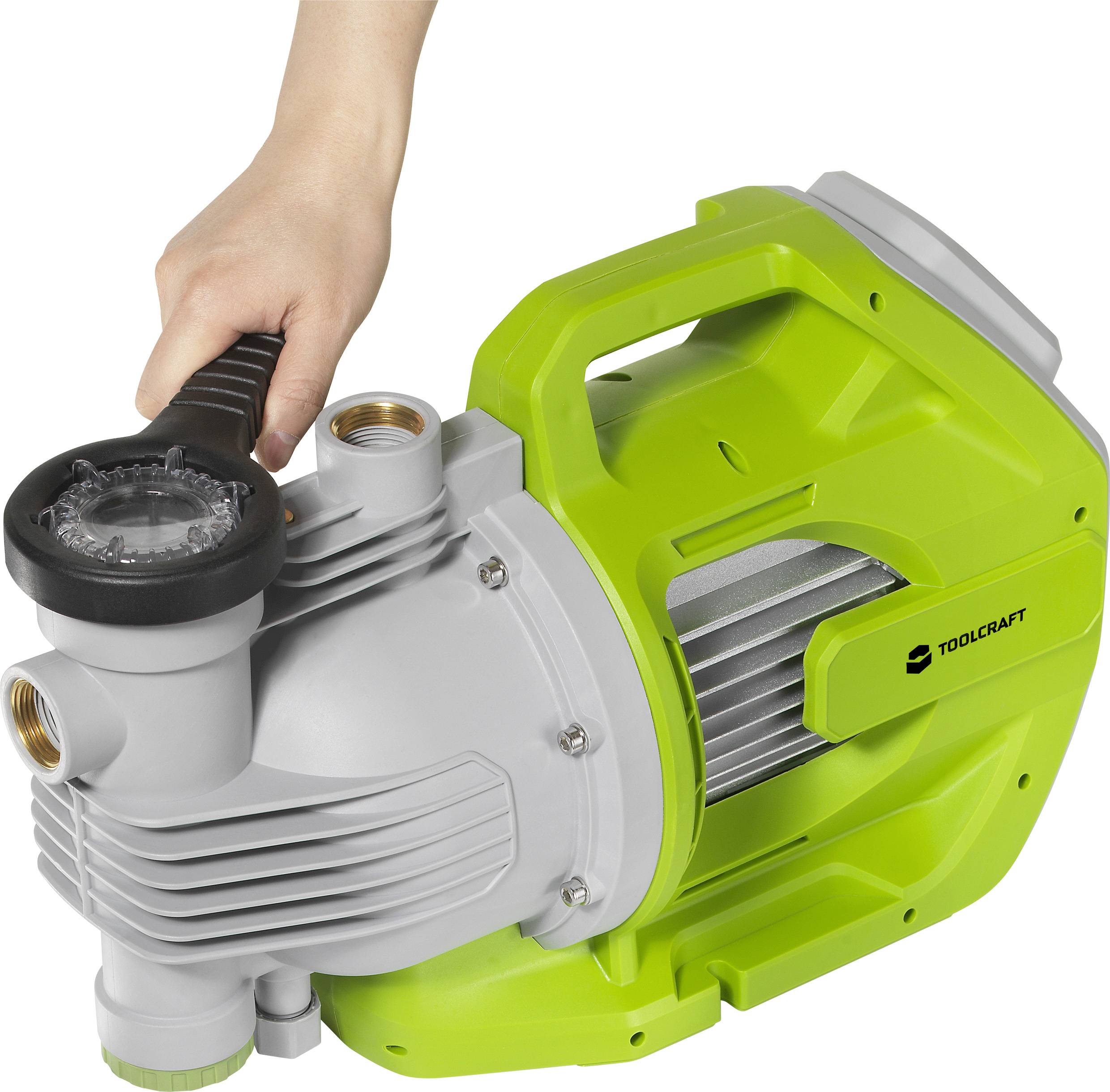 A hand is holding a green water pump by TOOLCRAFT with a handle, suitable for garden or household water tasks.