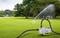A lawn pump with hoses in the foreground is irrigating a large, green lawn with several sprinkler systems in the background.