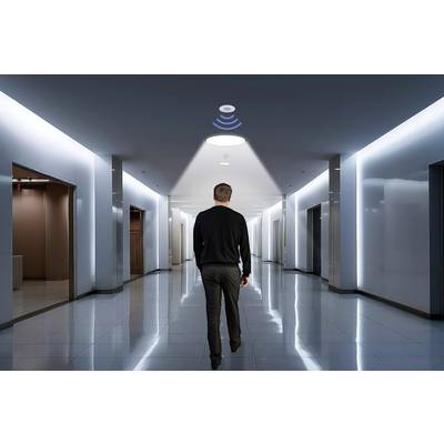 A man walks through a corridor with sensor lights that detect his movement and illuminate his path.