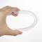 A human hand holds a transparent, flexible tube in a curved form against a neutral background.