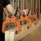 Three orange clamps are holding a piece of wood in place. A person is adjusting the clamps. They are used for woodworking.