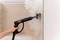 A hand holds a steam cleaner spraying steam onto a tiled wall to clean it.