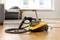 Steam cleaner on a wooden floor, ready for use. A grey sofa and a table in the background.
