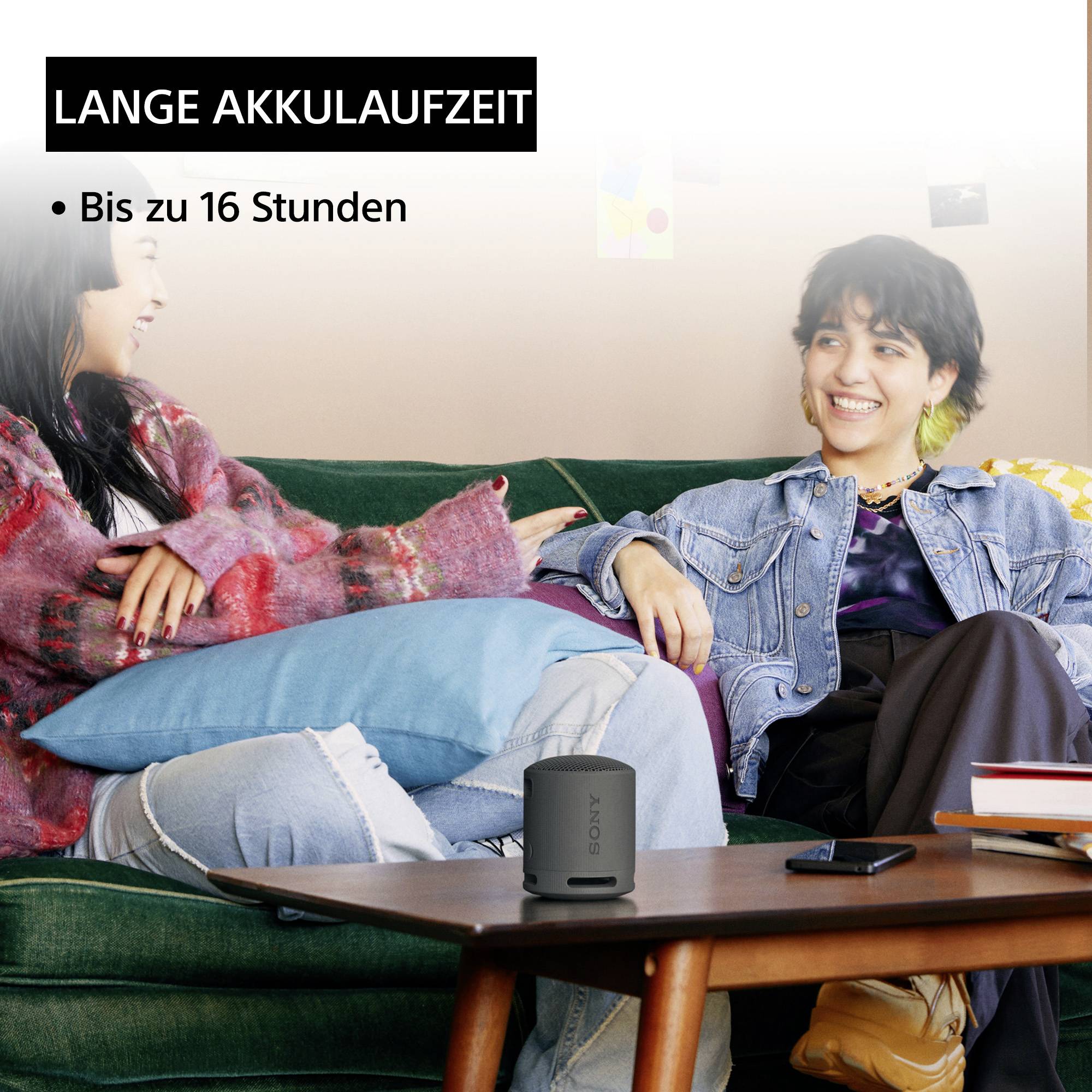 Two smiling people are sitting on a sofa. Text: 'Long battery life, up to 16 hours'.<br><br>Note: In this case, the translation is already very close to British English, with only minor nuances potentially being different from American English.