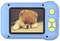 A small, fluffy puppy lies with a sad expression on a surface. In the foreground, a blue toy camera casing.