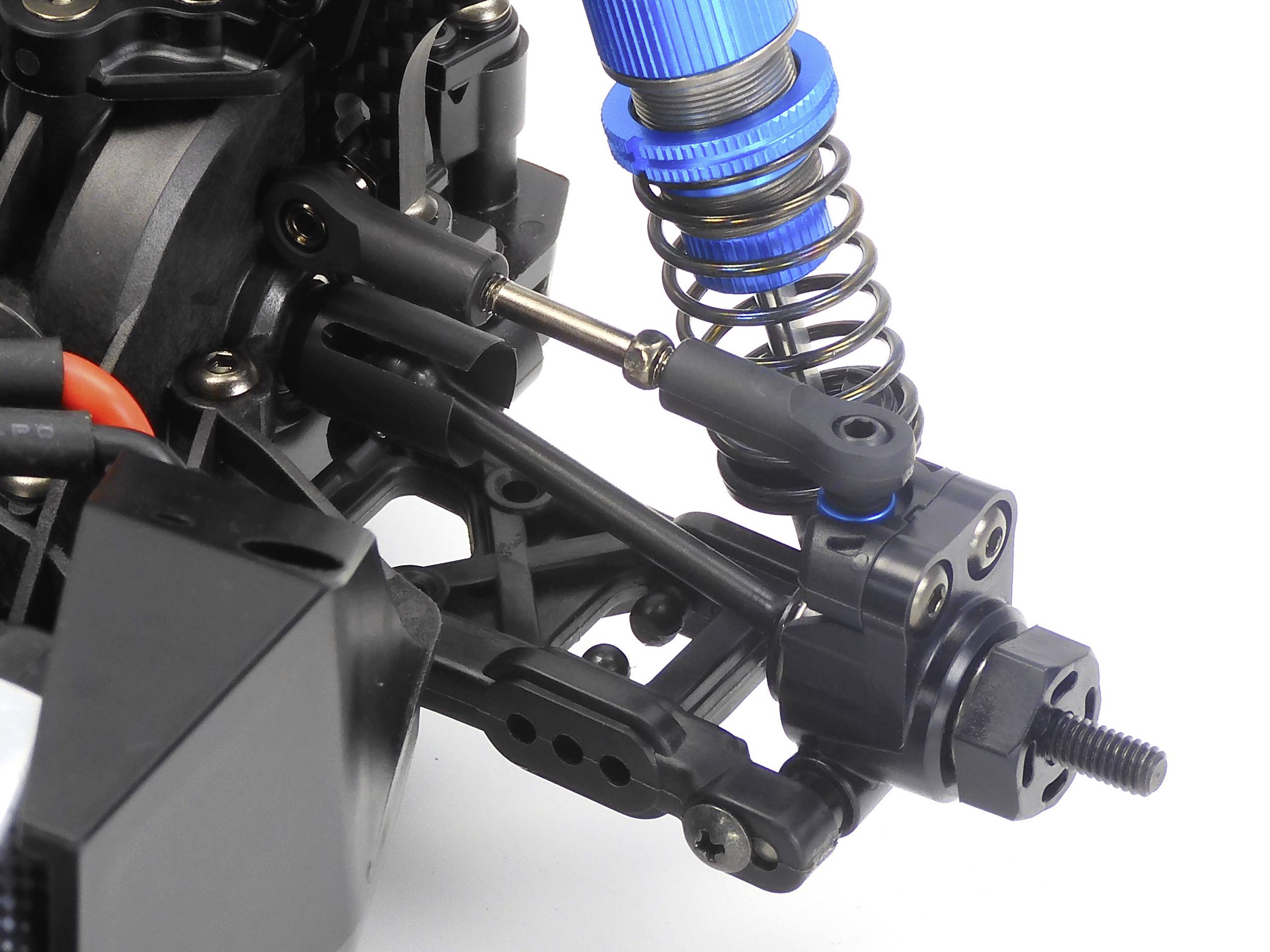 Close-up of a stripped shock absorber with a blue spring and black spring strut, mounted on an RC vehicle's front axle.