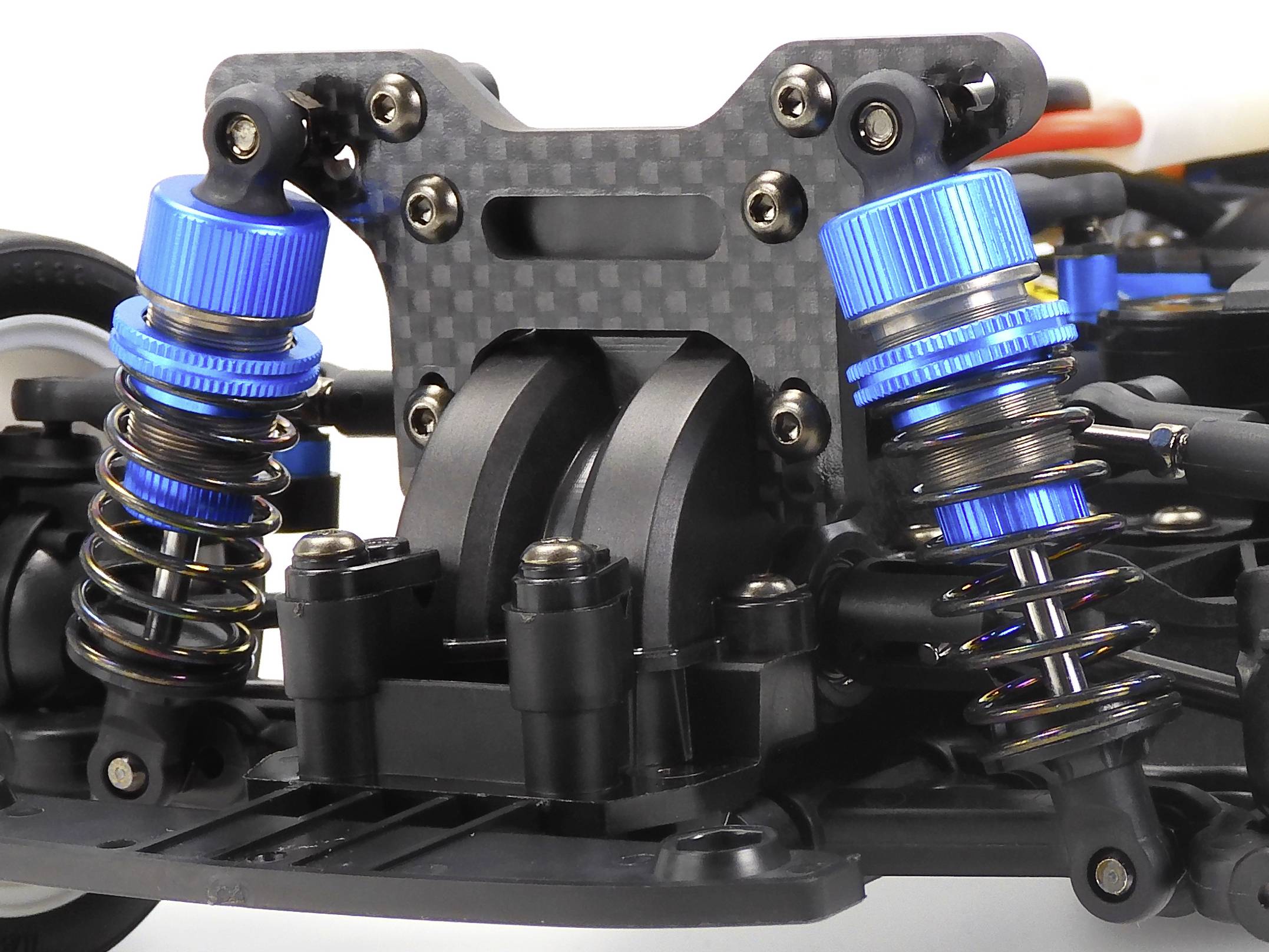 Close-up of the suspension of an RC vehicle with blue shock absorbers and carbon fibre material. Reveals technical details of the construction.