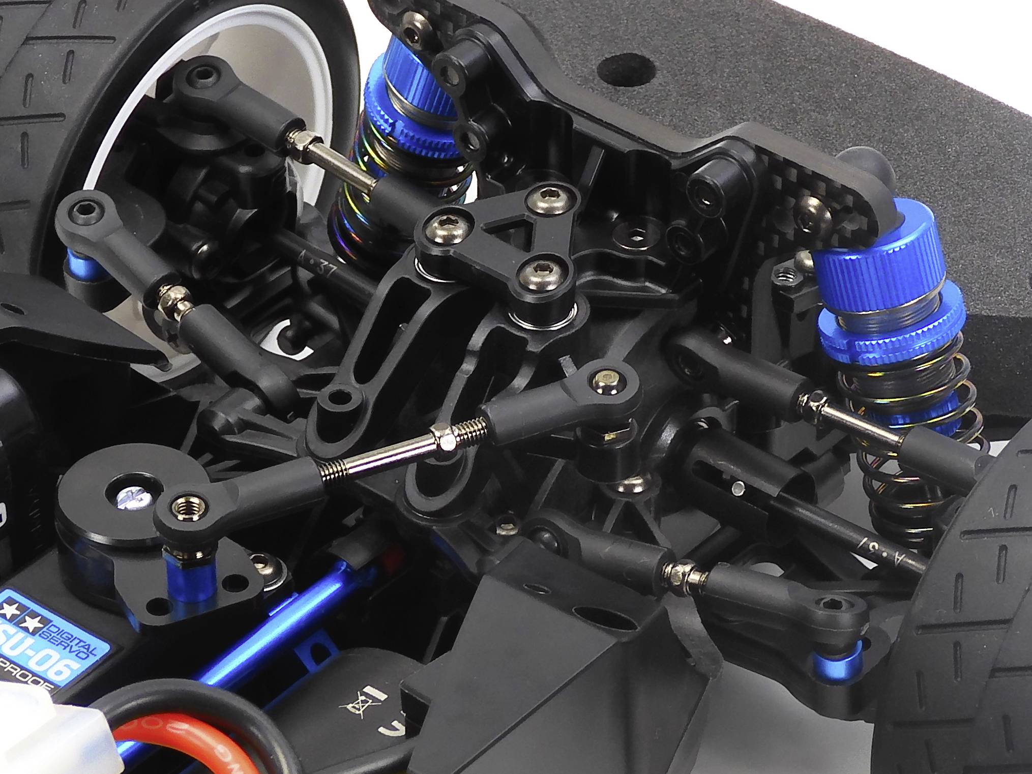 Close-up of a remote-controlled car showing the detailed suspension and shock absorbers, emphasising the technical construction and precision.
