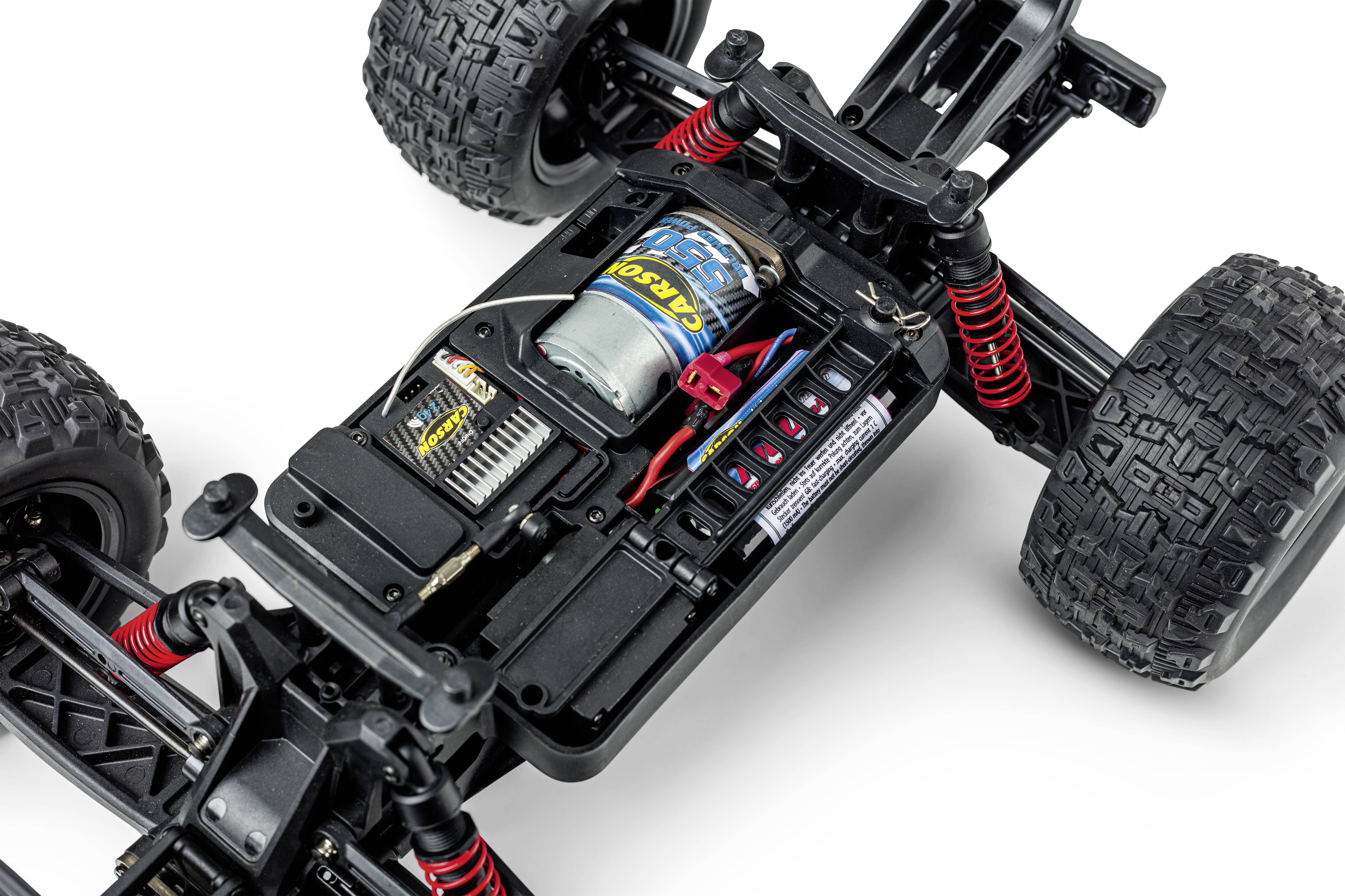 Remote-controlled car without bodywork, showing the engine, wiring, and suspension. View of the chassis and large off-road tyres.