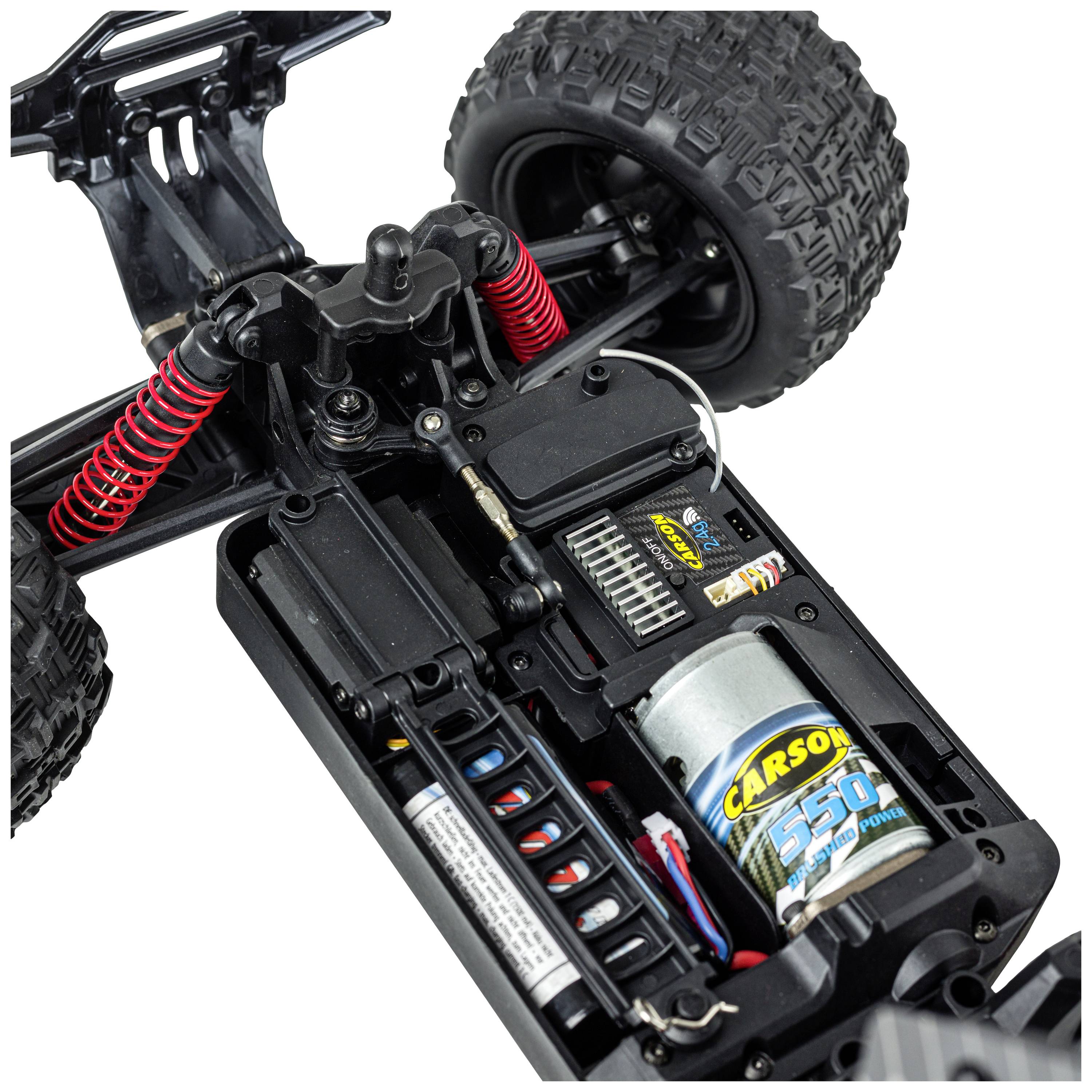 A remote-controlled car with an open chassis reveals its inner workings: the motor, battery compartment, and suspension are visible.