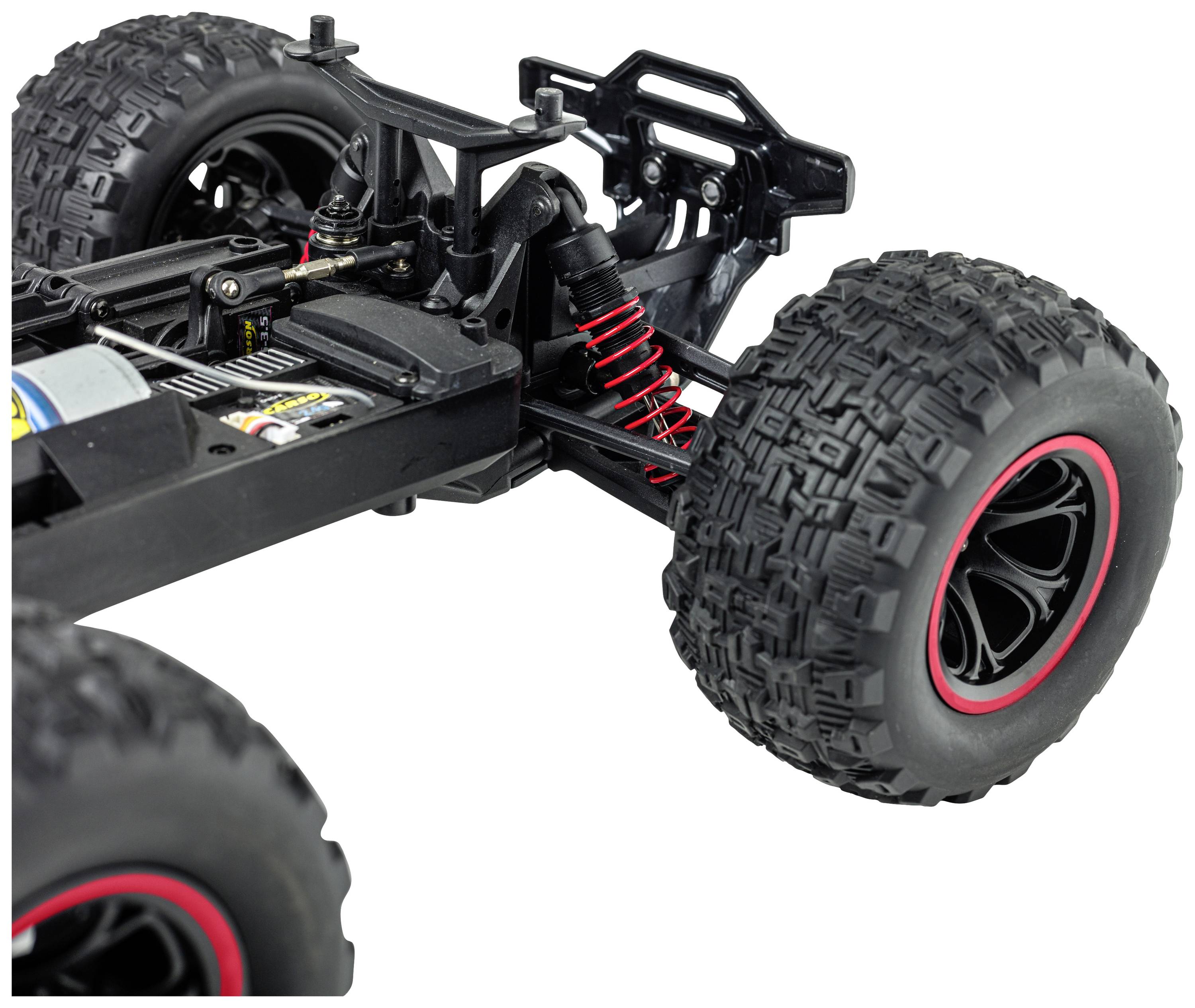 A remotely controlled car chassis with large off-road tyres and a red shock absorber, showing details of the suspension and wheel mounting.