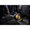 A yellow and black handheld vacuum cleaner is being used to clean the footwell of a car. A person is holding the handle of the device.