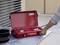 A hand is placing a red portable gas stove with two burners by 'Rothenberger Industrial' on an outdoor table.
