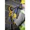 A person wearing a protective vest and helmet is drilling a round hole in a brick wall using a power tool.