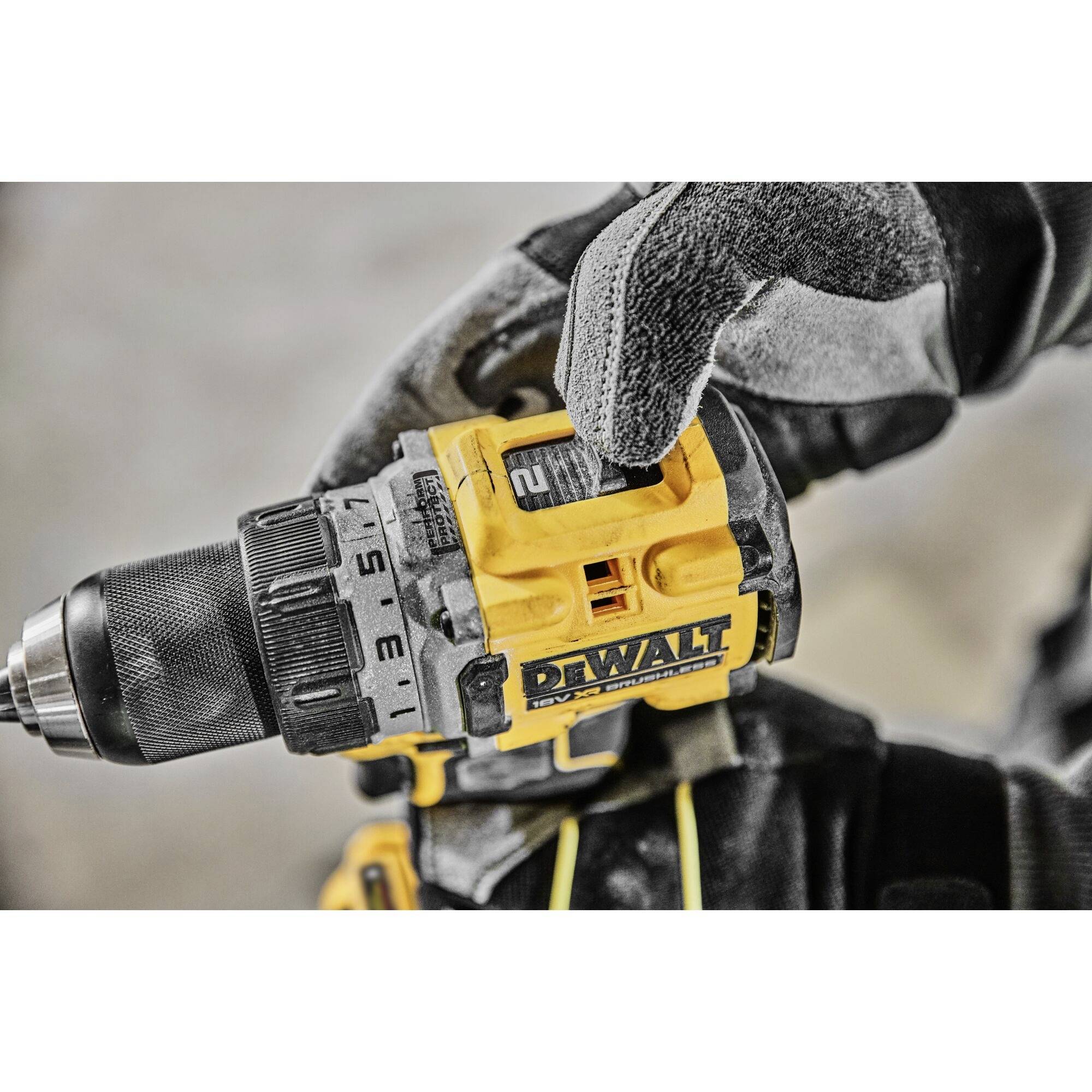 A person is holding a yellow cordless drill with a strong grip. The drill has multiple setting options and is ready to start drilling.