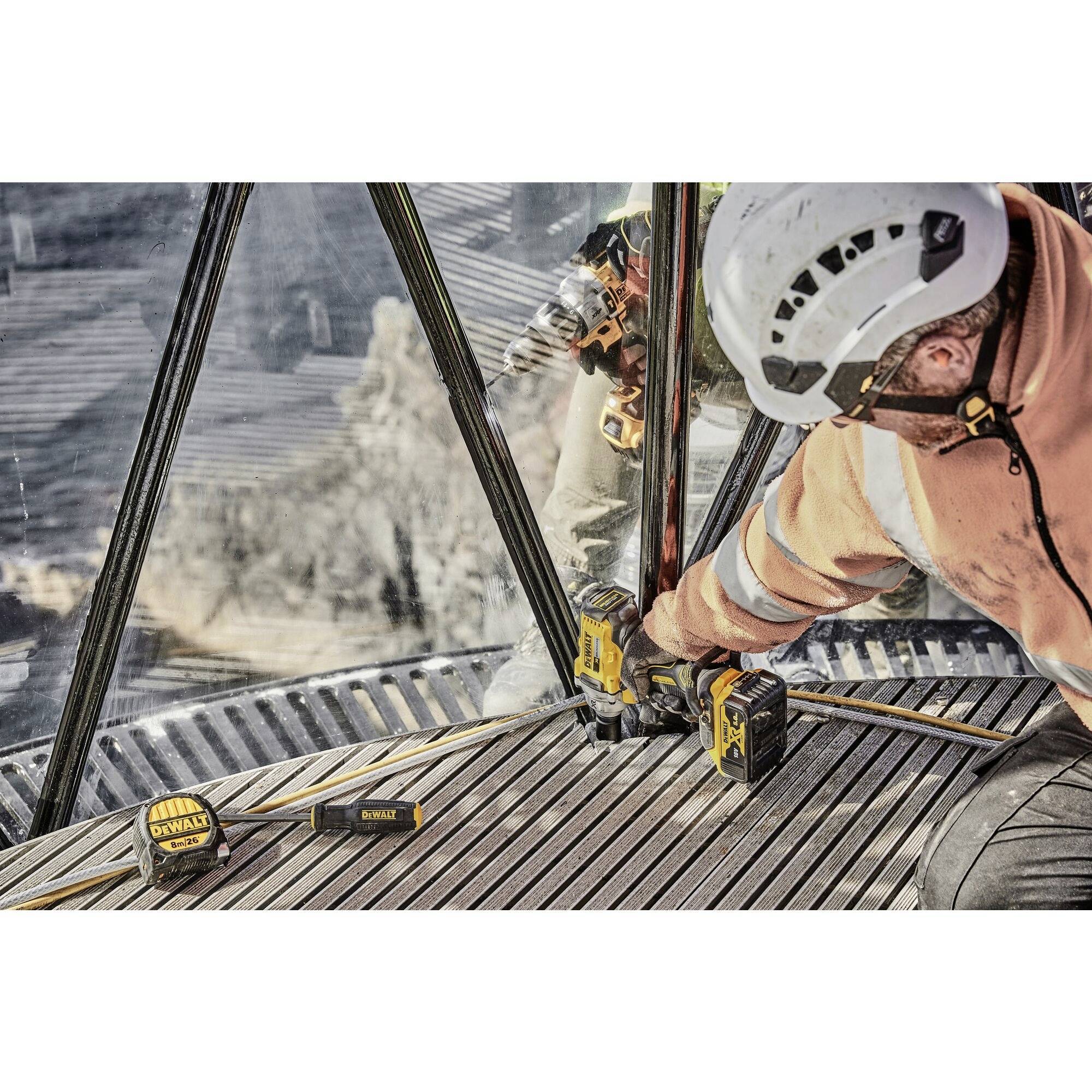 A person in work attire and a hard hat is operating a tool at a construction site or construction environment.