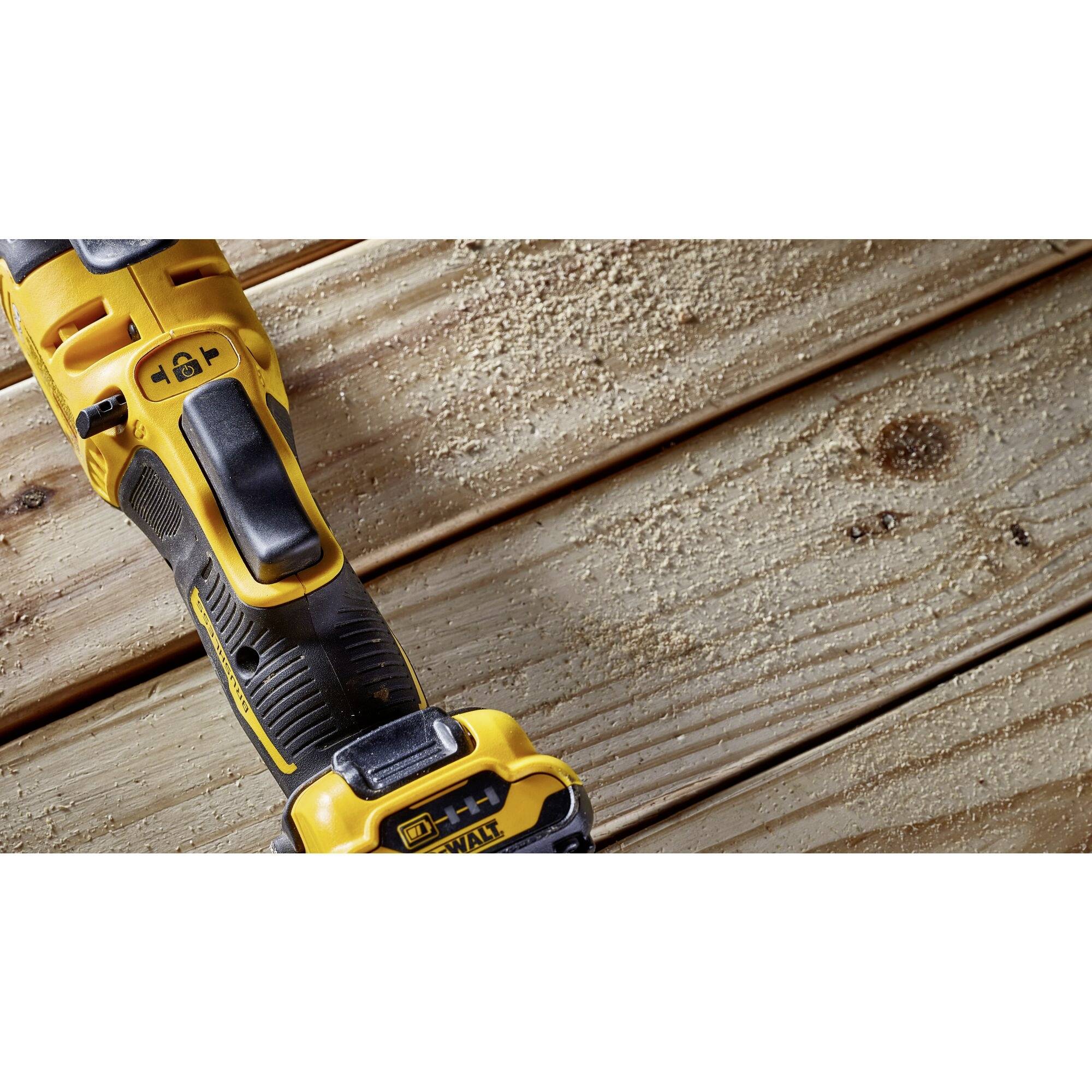 Close-up of a yellow power tool on a wooden background, surrounded by wood shavings. The tool displays multiple functions.