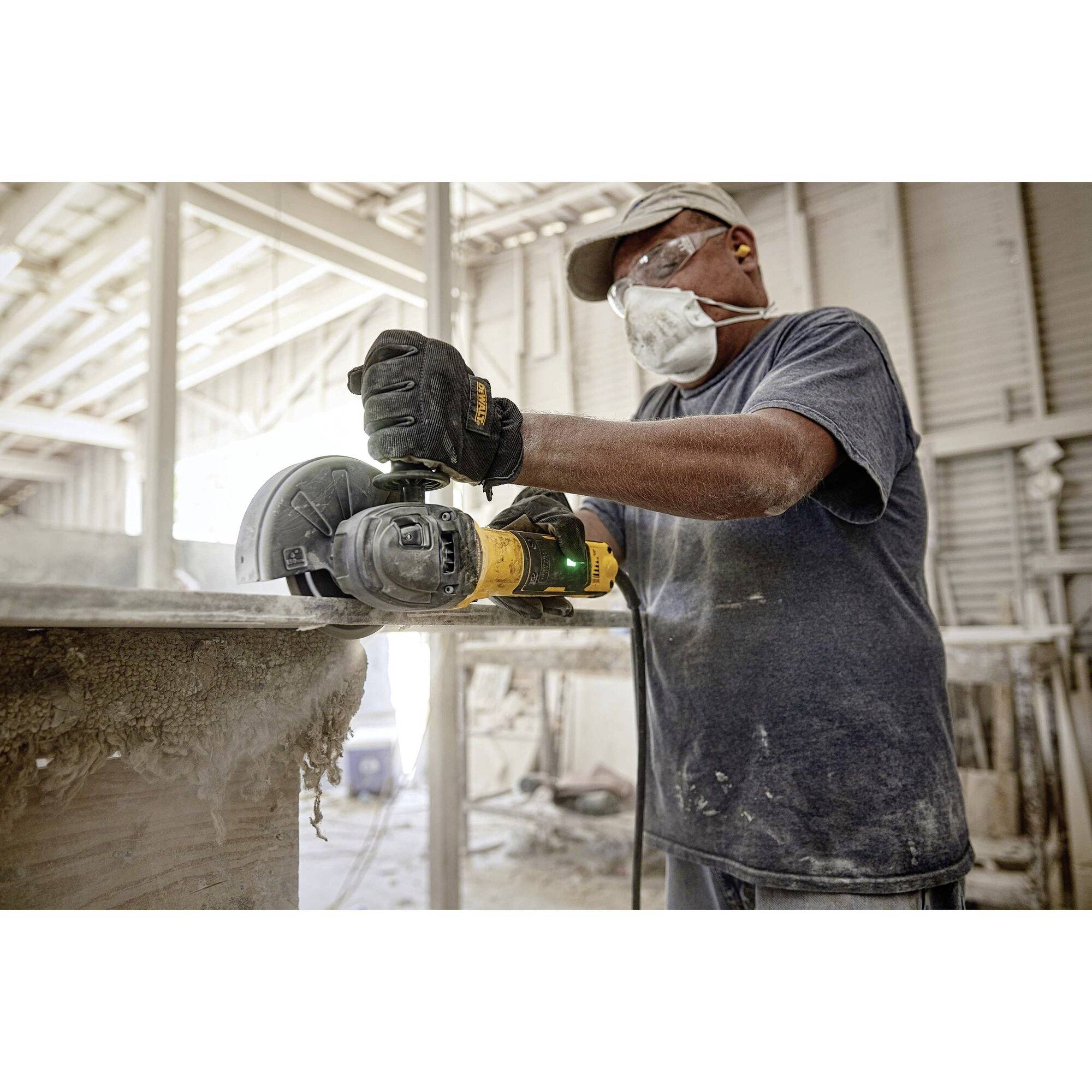 A tradesman is sanding wood with a chainsaw in a dusty workshop, wearing protective clothing and a respiratory mask.