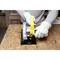 A person wearing protective gloves is using a yellow circular saw on a wooden board.