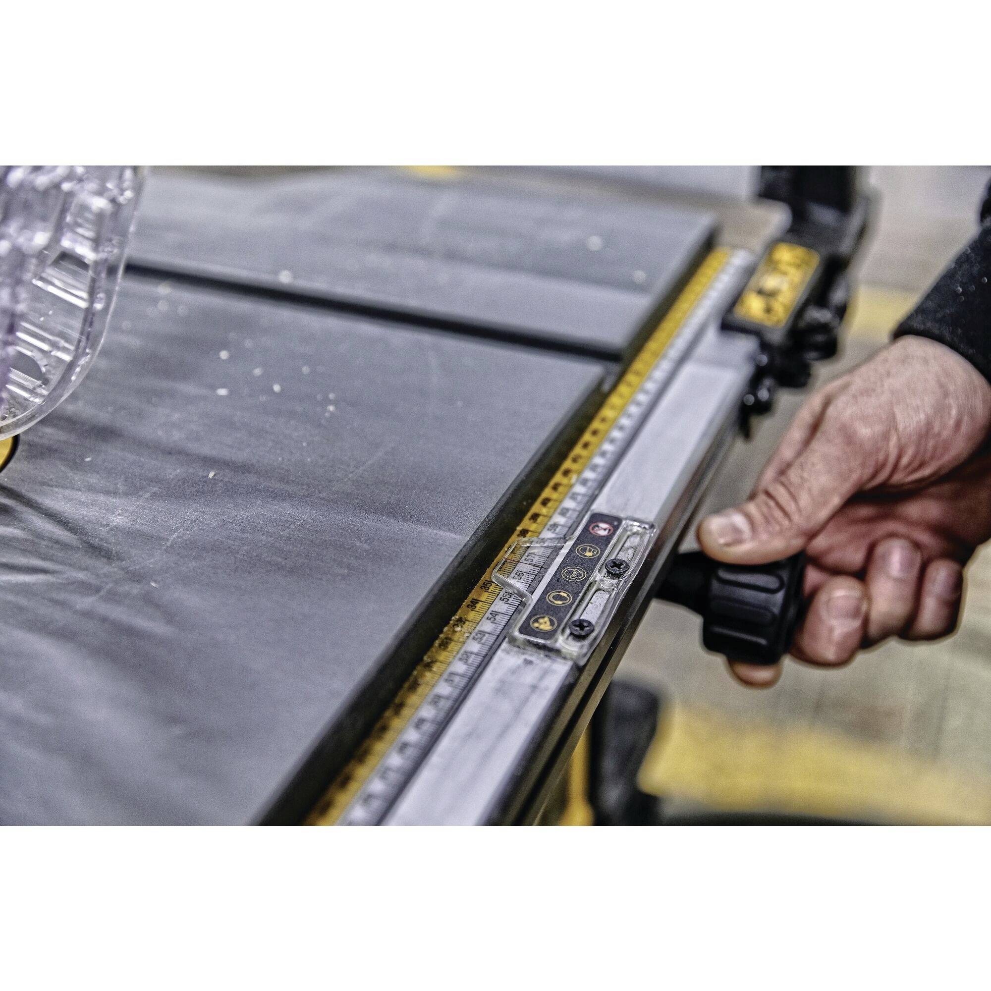 A hand adjusts the angle on a table saw fence. The fence has markings and a black adjustment knob.