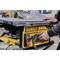 A person is operating a yellow table saw with the 'DEWALT' label, carefully adjusting its settings.