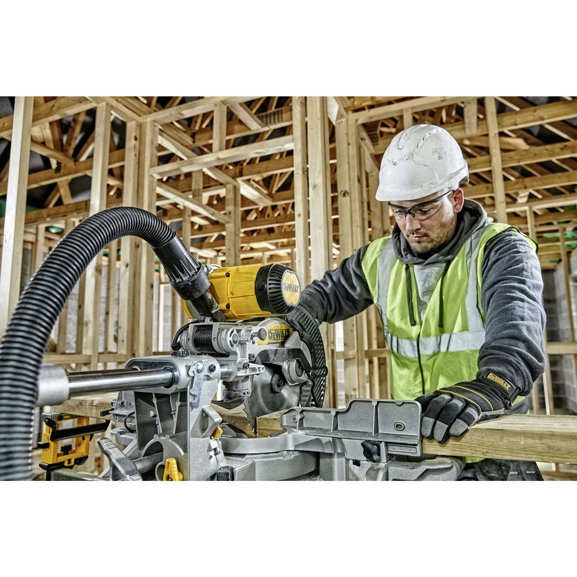 A construction worker in protective clothing operates an electric saw during timber frame construction, surrounded by wooden beams and joists.