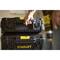 A person is lifting a black tool case with a yellow handle by Stanley. A drill is visible in the background.