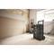 A person is working in a room that needs renovation, with walls in their raw state. Next to them stands a black toolbox on wheels.
