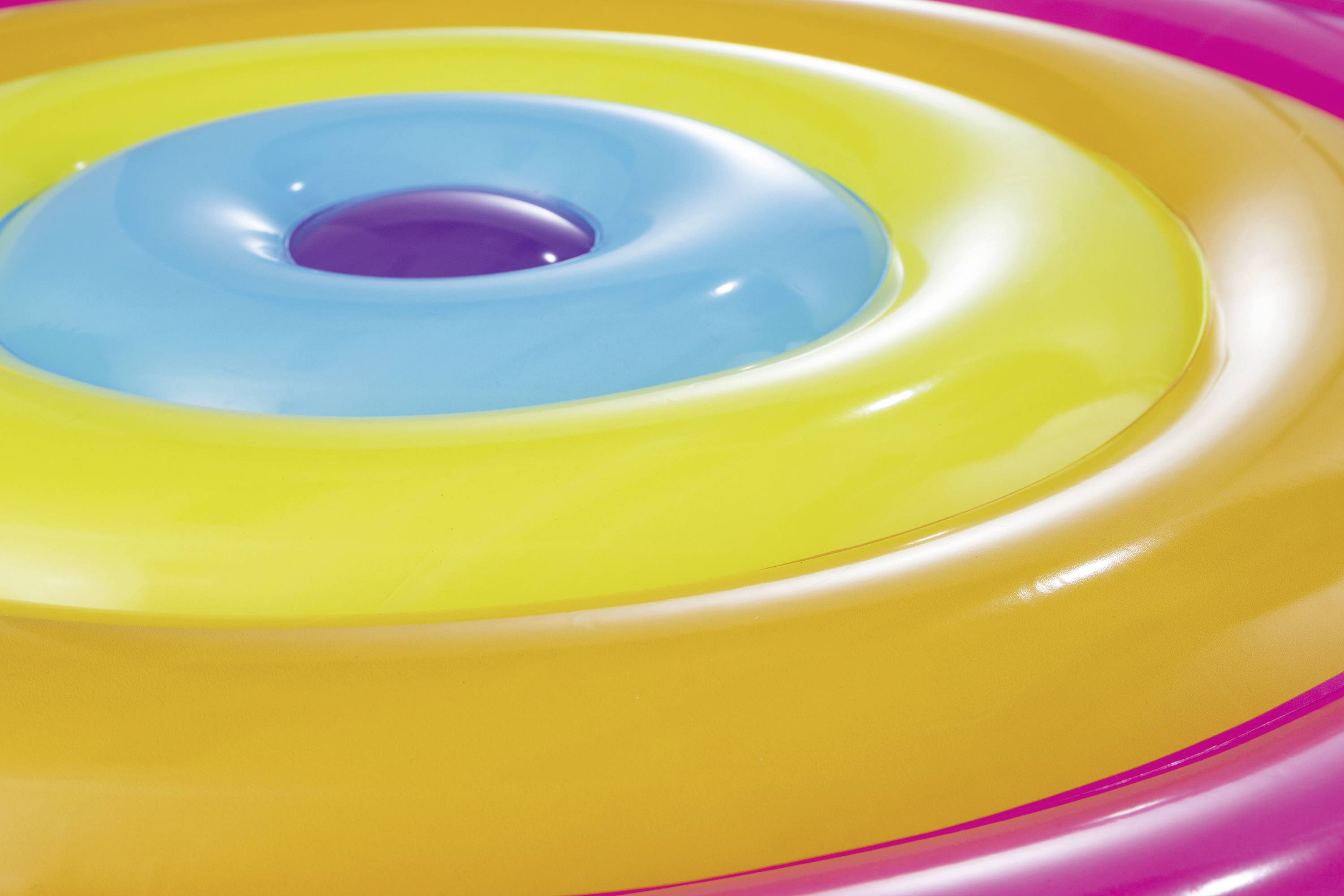 Colourful, inflatable swimming rings in vibrant hues (blue, yellow, orange, pink), stacked on top of each other and gleaming in the sunlight.