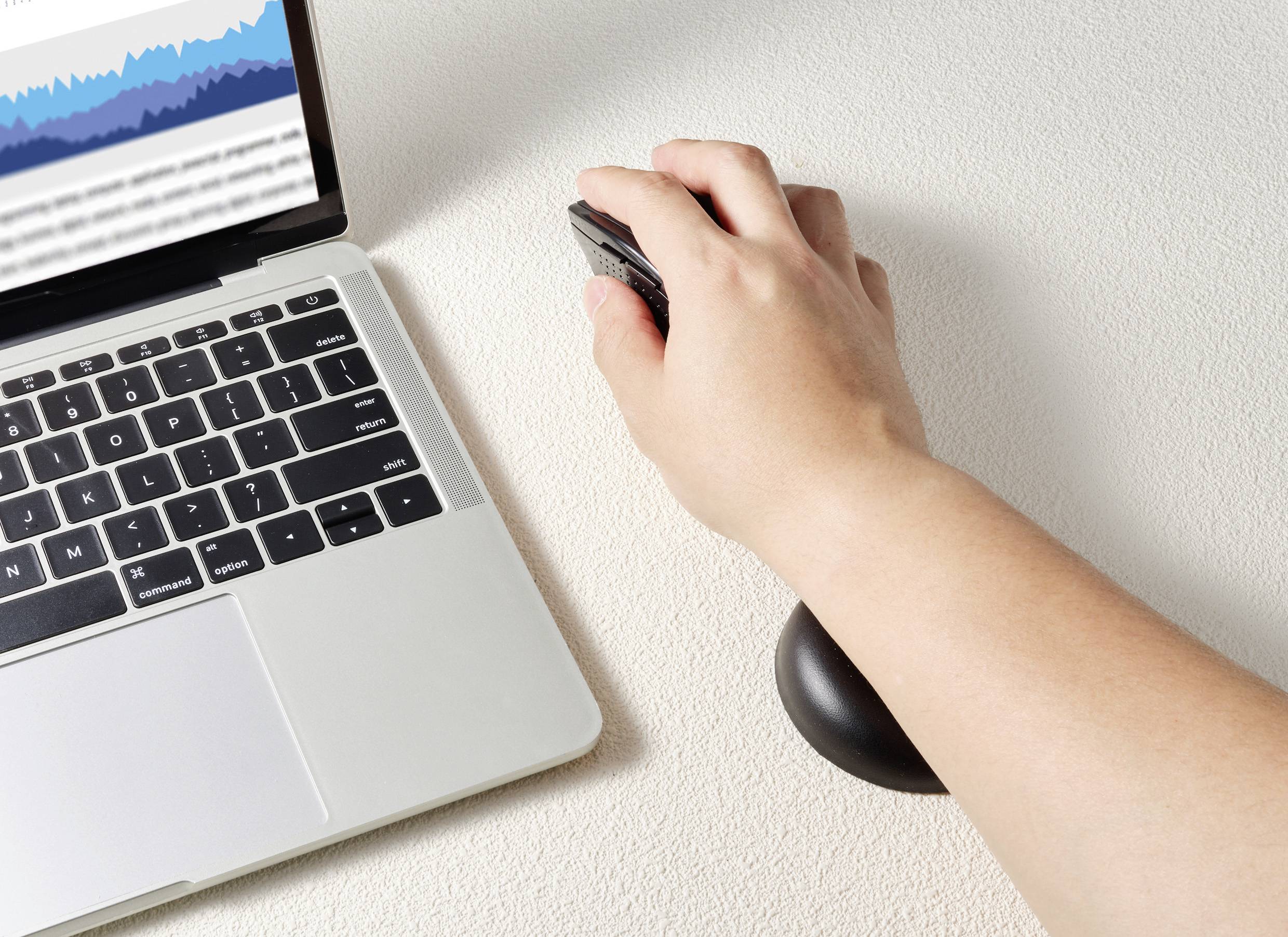 A hand is moving a computer mouse beside a laptop, with a diagram visible on the screen.