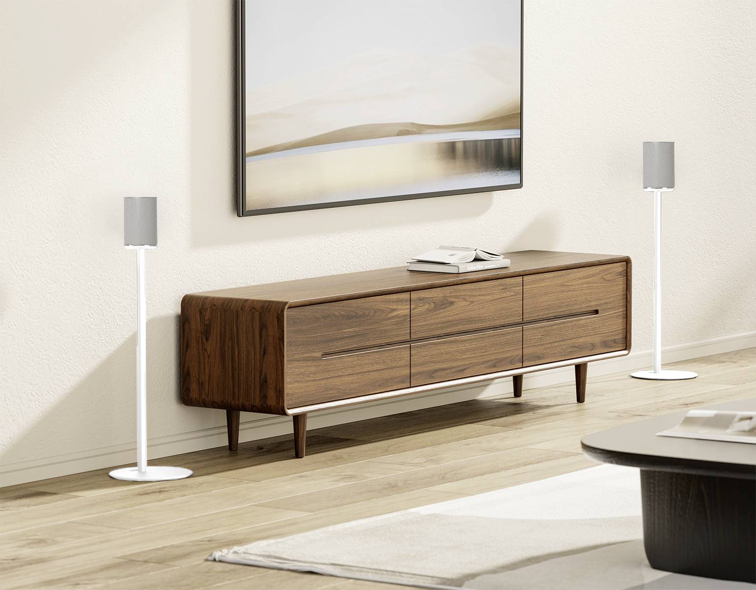 Wooden console with drawers against a light-coloured wall, with two books placed on top. White speakers stand to the left and right. A modern, minimalist living environment.