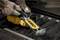 'Hands wearing gloves operating a yellow power tool, labeled "Dewalt," on a metal surface, creating sparks as it cuts.'