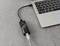 A laptop is connected via an Ethernet cable through a USB adapter, which is lying on a grey table.