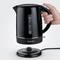 'Black electric kettle with handle, maximum capacity 1.7 litres, sits on base, hand holding the handle.'