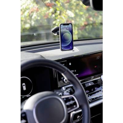 Smartphone mounted on a holder in a car, displaying a time. Steering wheel and part of the dashboard visible in the foreground. Background blurred.