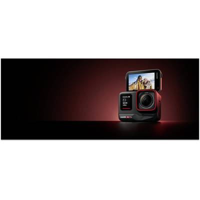 A black action camera with a display shows a selfie photo of two people. The background is dimly lit in dark red.