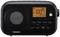 A portable black radio with a speaker on the left and a digital display on the right, showing 'FM 100.7' and the time.