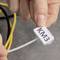 A hand holds a cable tie label with the inscription 'KM3'. Yellow and black cables are visible in the background.